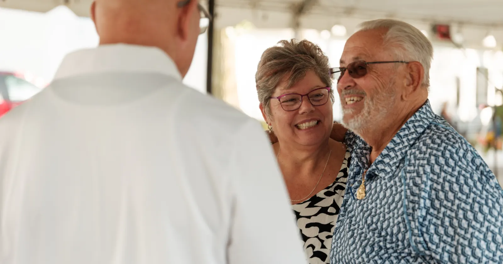 Two happy seniors talking with a financial planner outdoors.